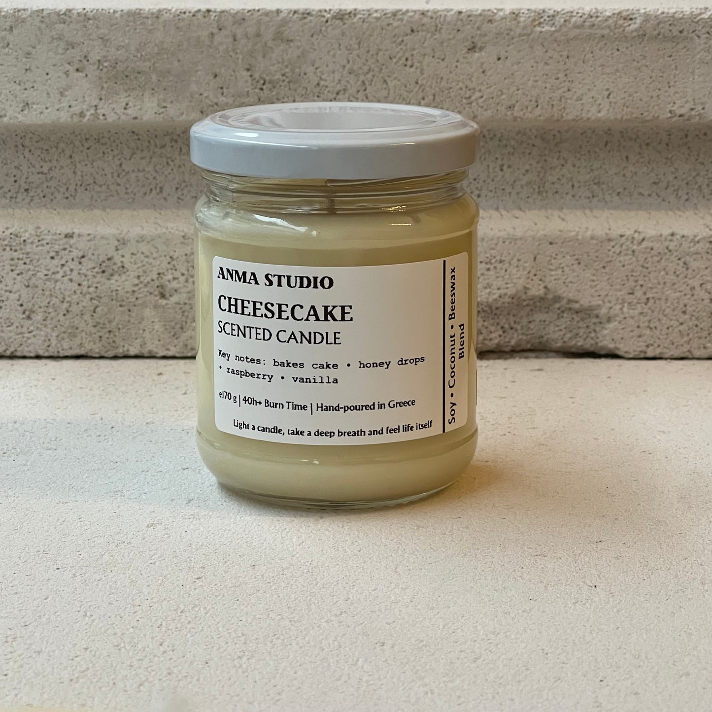 Χειροποίητο αρωματικό κερί Cheesecake της Anma Studio σε γυάλινο δοχείο με μεταλλικό καπάκι, φτιαγμένο από μείγμα σόγιας, καρύδας και μελισσοκεριού.