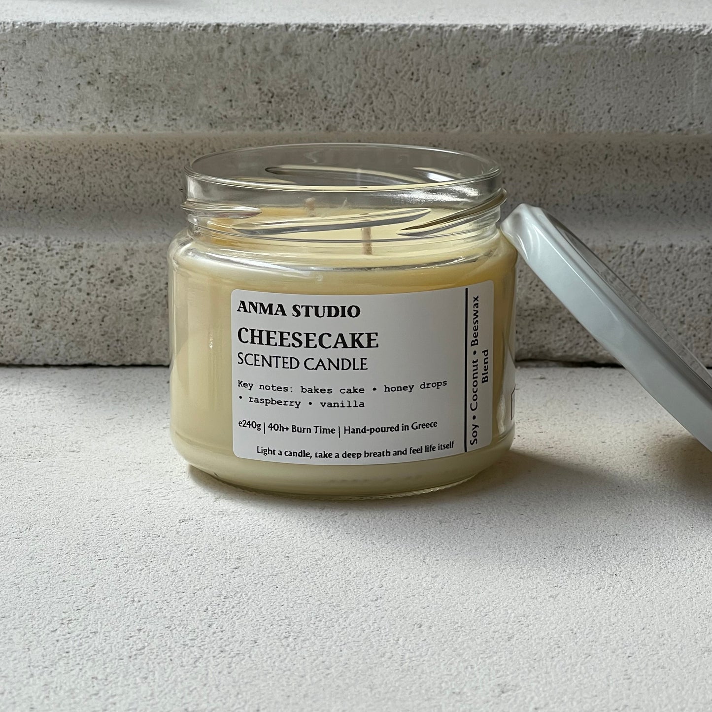 Χειροποίητο αρωματικό κερί Cheesecake της Anma Studio σε γυάλινο δοχείο με μεταλλικό καπάκι, φτιαγμένο από μείγμα σόγιας, καρύδας και μελισσοκεριού.