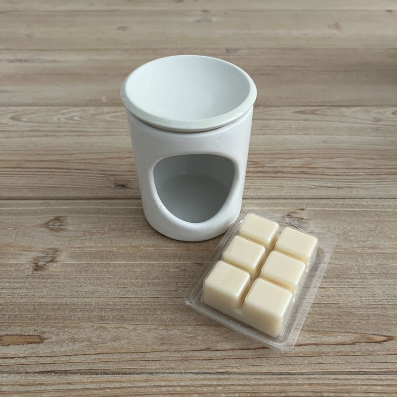 Χειροποίητα wax melts από φυσικό κερί σόγιας και καρύδας σε λευκό χρώμα, 6 αρωματικοί κύβοι σε διάφανη συσκευασία επάνω σε ξύλινη επιφάνεια.